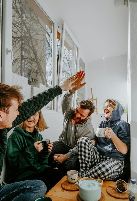 Happy group of friends hanging out in a living room giving a high five