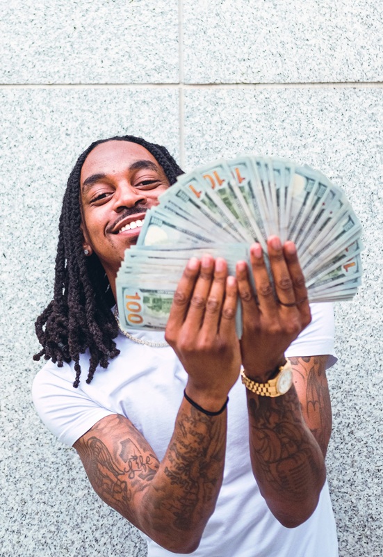 Man holding a stack of hundred dollar bills